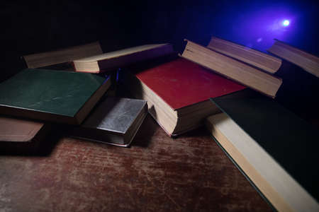 A stack of old books. Vintage book on wooden table. Magic lightning around a glowing book in the...