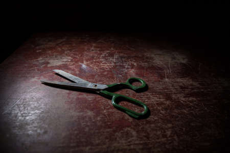 Old tailor`s scissors on wooden table in low light. Artwork decoration with toned foggy backlight....