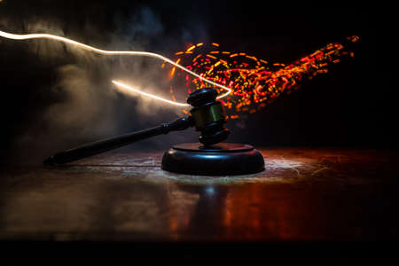 Law, justice concept. Creative artwork table decoration with mallet of the judge on dark foggy background with colorful light. Selective focusの写真素材