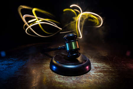 Law, justice concept. Creative artwork table decoration with mallet of the judge on dark foggy background with colorful light. Selective focusの写真素材
