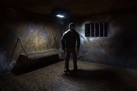 Man in prison man behind bars concept. Old dirty grunge prison miniature. Dark prison interior creative decoration. Selective focusの写真素材