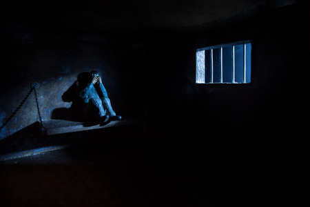 Man in prison man behind bars concept. Old dirty grunge prison miniature. Dark prison interior creative decoration. Selective focusの写真素材