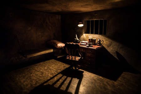 Man in prison man behind bars concept. Old dirty grunge prison miniature. Dark prison interior creative decoration. Miniature table inside. Selective focusの写真素材