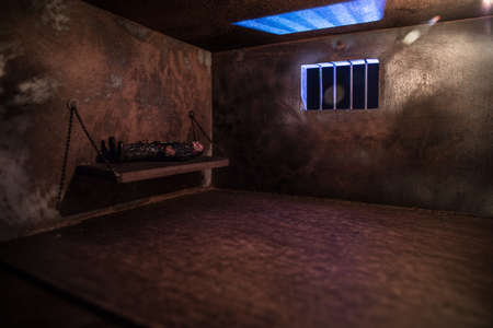 Man in prison man behind bars concept. Old dirty grunge prison miniature. Dark prison interior...