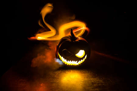 Halloween horror concept with glowing pumpkin. A realistic dollhouse living room with furniture, door and window at night. Scary zombies outside. Selective focus.の写真素材