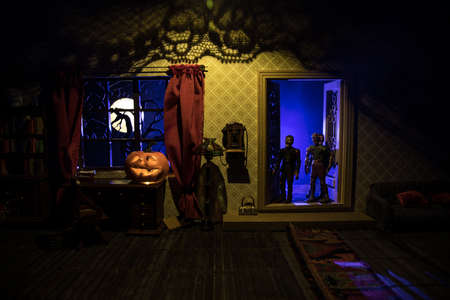 Halloween horror concept with glowing pumpkin. A realistic dollhouse living room with furniture, door and window at night. Scary zombies outside. Selective focus.の写真素材