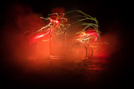 Drink, broken glass concept. Broken glasses on wooden table at dark toned background with fog....