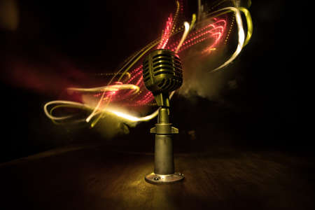 Retro style microphone on background with backlight. Vintage silver Microphone for sound, music, karaoke. Speech broadcast equipment. Live pop, rock musical performance. Selective focusの写真素材