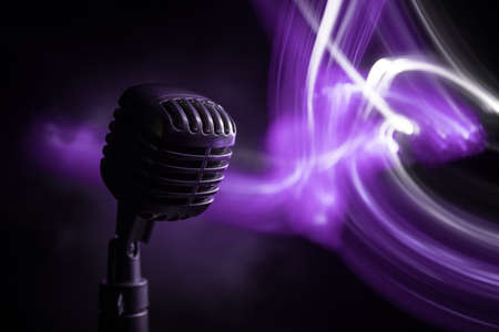 Retro style microphone on background with backlight. Vintage silver Microphone for sound, music, karaoke. Speech broadcast equipment. Live pop, rock musical performance. Selective focusの写真素材