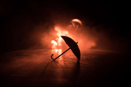 Silhouette of umbrella miniature on table with dark toned foggy background. Creative concept. Selective focusの写真素材