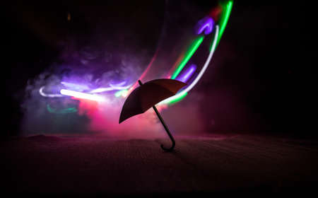 Silhouette of umbrella miniature on table with dark toned foggy background. Creative concept. Selective focusの写真素材
