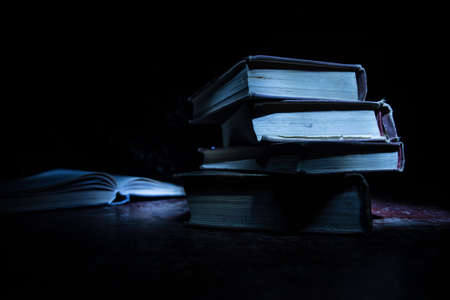 A stack of old books. Vintage book on wooden table. Magic lightning around a glowing book in the...