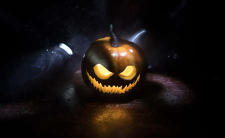 Halloween pumpkin smile and scary eyes for party night. Close up view of scary Halloween pumpkin with eyes glowing inside at black background. Selective focusの写真素材