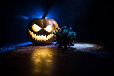 Halloween during Corona virus global pandemic concept. Glowing pumpkins and Covid novel on dark with...