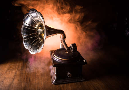 Music concept. Old gramophone on a dark background. Retro gramophone with disc on wooden table with toned backlight. Selective focusの写真素材