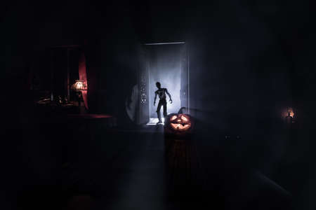 Halloween horror concept with glowing pumpkin. A realistic dollhouse living room with furniture,...