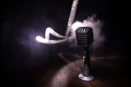 Retro style microphone on background with backlight. Vintage silver Microphone for sound, music, karaoke. Speech broadcast equipment. Live pop, rock musical performance. Selective focusの写真素材