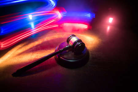 Law, justice concept. Creative artwork table decoration with mallet of the judge on dark foggy background with colorful light. Selective focusの写真素材