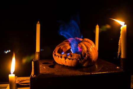 Horror Halloween concept. Close up view of scary dead Halloween pumpkin glowing at dark background. Rotten pumpkin head. Selective focusの写真素材