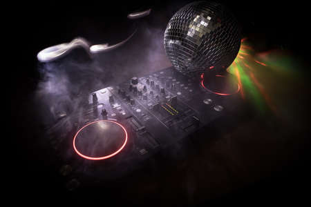 Club music concept. DJ console deejay-mixing desk in dark with colorful light. Mixer equipment...