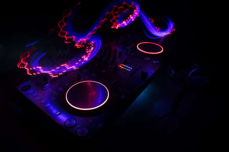 Club music concept. DJ console deejay-mixing desk in dark with colorful light. Mixer equipment...