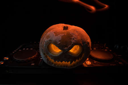 Halloween pumpkin on a dj table with headphones on dark background with copy space. Happy Halloween...