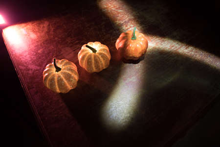 Halloween during Corona virus global pandemic concept. Glowing pumpkins and Covid novel on dark with thematic spooky decorations. Halloween pumpkin on foggy backlight. Selective focusの写真素材