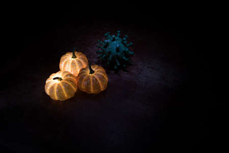 Halloween during Corona virus global pandemic concept. Glowing pumpkins and Covid novel on dark with thematic spooky decorations. Halloween pumpkin on foggy backlight. Selective focusの写真素材