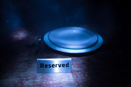 Reserved sign on the table. A tag of reservation placed on the wood table. Metal tag with...