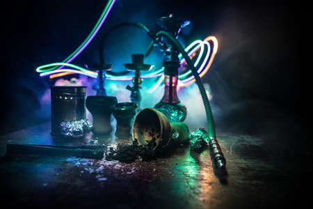 Shisha concept. Preparing shisha on table. Used shisha bowl on wooden table. Dark atmosphere with light. Selective focus.の写真素材