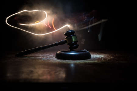 Law, justice concept. Creative artwork table decoration with mallet of the judge on dark foggy background with colorful light. Selective focusの写真素材