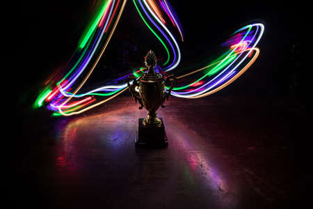 Golden trophy cup on table dark background with copy space. Creative artwork decoration with toned...
