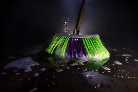 close-up brush the floor on a dark background with light and fog. Broom in dark. Cleaning concept....