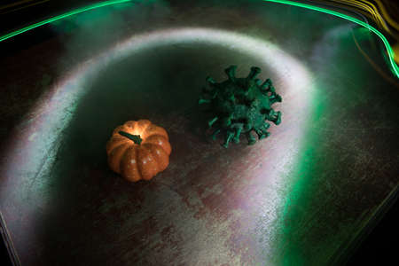 Halloween during Corona virus global pandemic concept. Glowing pumpkins and Covid novel on dark with thematic spooky decorations. Halloween pumpkin on foggy backlight. Selective focusの写真素材