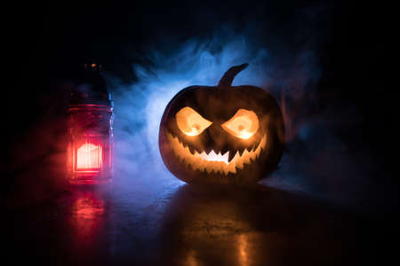 Halloween pumpkin smile and scary eyes for party night. Close up view of scary Halloween pumpkin with eyes glowing inside at black background. Selective focus