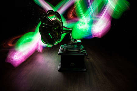 Music concept. Old gramophone on a dark background. Retro gramophone with disc on wooden table with toned backlight. Selective focusの写真素材