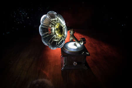 Music concept. Old gramophone on a dark background. Retro gramophone with disc on wooden table with toned backlight. Selective focusの写真素材