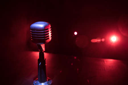 Retro style microphone on background with backlight. Vintage silver Microphone for sound, music, karaoke. Speech broadcast equipment. Live pop, rock musical performance. Selective focusの写真素材