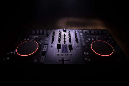 Club music concept. DJ console deejay-mixing desk in dark with colorful light. Mixer equipment entertainment DJ station. Selective focus