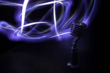 Retro style microphone on background with backlight. Vintage silver Microphone for sound, music, karaoke. Speech broadcast equipment. Live pop, rock musical performance. Selective focusの写真素材