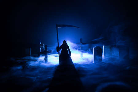 Scary view of grim reaper at cemetery with spooky cloudy sky and fog, Horror Halloween concept. Selective focusの写真素材