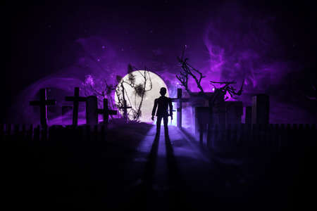 Scary view of zombies at cemetery dead tree, moon, church and spooky cloudy sky with fog, Horror...