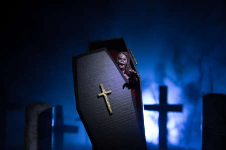 Creative artwork. Miniature wooden coffin with zombie inside. Scary view of zombies at cemetery....