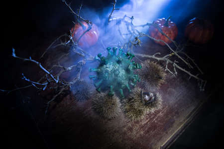 Halloween during Corona virus global pandemic concept. Glowing pumpkins and Covid novel on dark with...