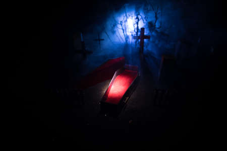 Creative artwork. Miniature wooden coffin with zombie inside. Scary view of zombies at cemetery....
