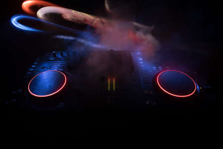Club music concept. DJ console deejay-mixing desk in dark with colorful light. Mixer equipment...