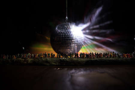 Clublife creative concept. Crowd miniature standing at big disco mirror ball with lights. Night club...