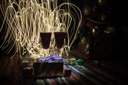 Glass of wine with Christmas decoration. Red wine in crystal glass with bottle on colorful carpet...