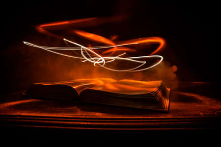 A stack of old books. Vintage book on wooden table. Magic lightning around a glowing book in the...