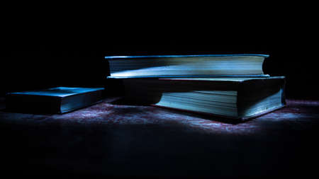 A stack of old books. Vintage book on wooden table. Magic lightning around a glowing book in the...